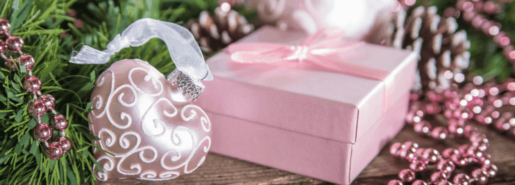 Un cadeau de couleur rose posé par mi des décoration de Noël