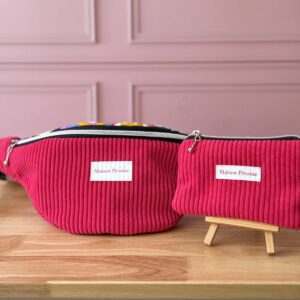 banane-fuschia Parure Maison Pivoine fuchsia : sac banane XXL et pochette assortie présentés sur un support en bois.