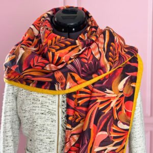 Zoom sur le chèche artisanal en viscose fleurie rouge, orange et bordeaux, doublé d’un tissu sweat jaune. Accessoire chaud et unique, cousu main en France.