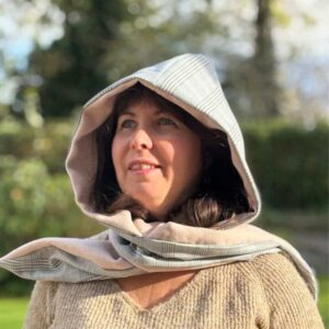 Femme portant l'écharpe capuche Nénuphar drapée sur les épaules en Prince de Galles beige