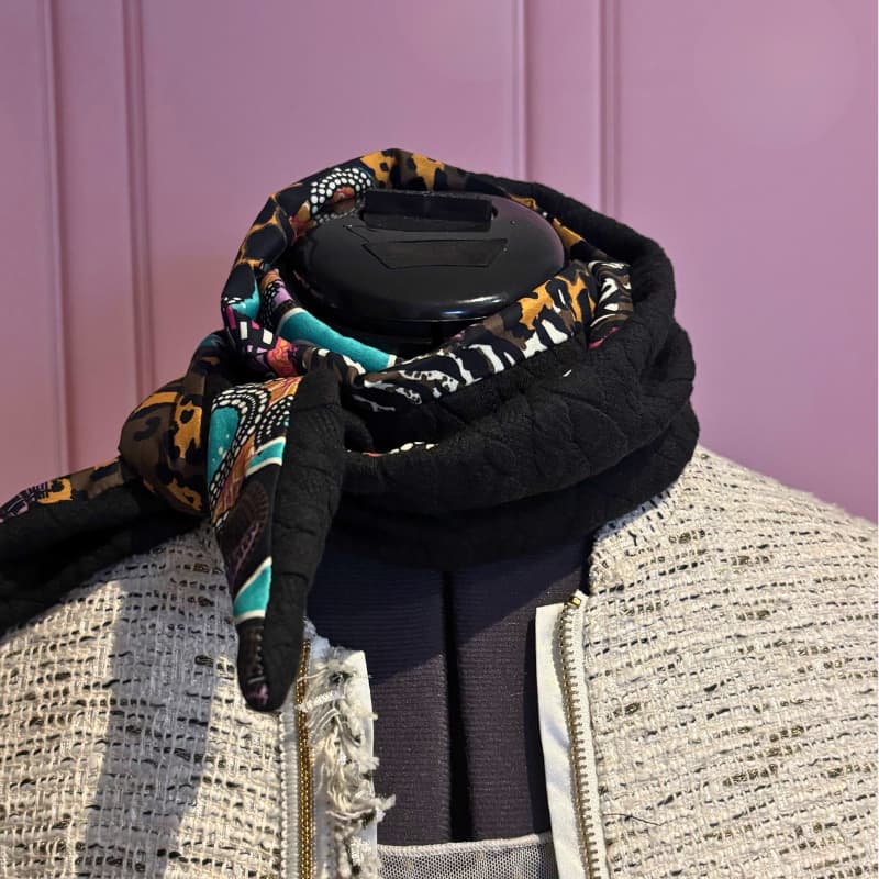 Foulard Sophie Scarf en laine tressรฉe noire et viscose colorรฉe, nouรฉ รฉlรฉgamment sur un buste dโexposition.