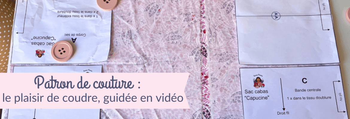 Vue de dessus d'un plan de travail de couture présentant les pièces d'un patron papier pour le « Sac cabas Capucine ». Les pièces blanches, maintenues sur un tissu rose à motifs par de gros boutons roses faisant office de poids, indiquent les instructions de coupe : « Corps de sac A » et « Bande centrale C ». Une bannière rose en bas à gauche affiche le texte : « Patron de couture : le plaisir de coudre, guidée en vidéo