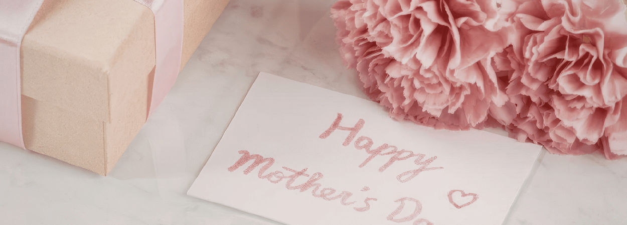 fête des mère, une carte avec une fmeur déposé a coté d'un cadeau